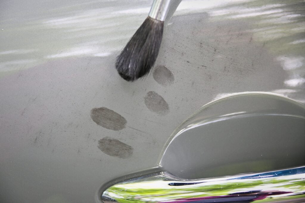 CSIs at work fingerprinting a car with powder and a brush